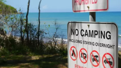 "No Camping" sign with symbols on a beachfront.