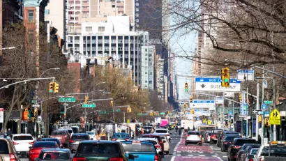 Busy New York city street with red painted bus-only lane on right.