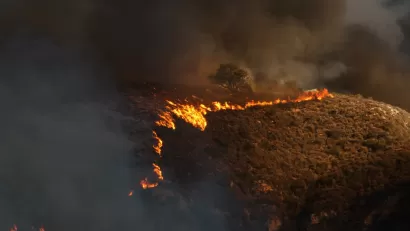 Line of wildfire moving across dry hillside in Malibu, California during 2018 Woolsey fire.