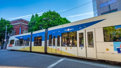 White and blue TriMet MAX light rail train on street in Portland, Oregon.