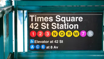 Close-up of New York City subway sign for Times Square 42nd St Station with colored dots indicating various train lines.