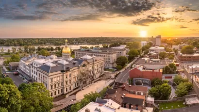 Aerial view of Trenton, New Jersey with gold state capitol down in foreground and golden hour sky.