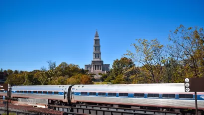 Amtrak train passing on bridge with historic tower in background in Alexandria, Virginia.