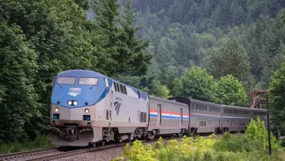 AMtrak train passing through dense green forest in Index, Washington.