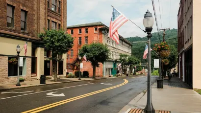 Street with historic buildings and American flag hanging from lamppost in downtown Hinton, West Virginia.