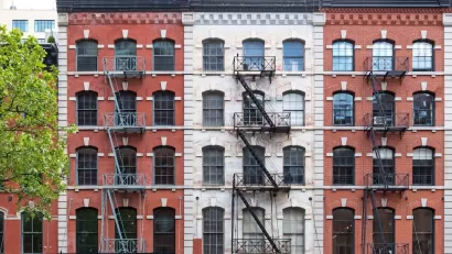 Brick New York City apartment buildings with fire escapes.