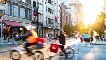 Two delivery bikes riding through intersection in New York City.