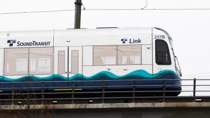 White and blue Sound Transit light rail train on elevated rail in Seattle, Washington.