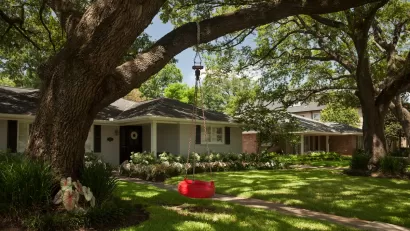 Small house with a red tire swing in front yard in Houston, Texas.