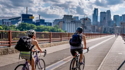 Two people on bikes riding toward downtown Minneapolis, Minnesota on Stone Arch Bridge.