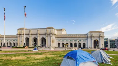 Several tents set up by unhoused residents on green lawn in front of neoclassical Union Station building in Washington D.C.
