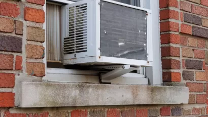Close-up of window-mounted air conditioning unit on outside of red brick building