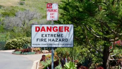 "Danger Extreme Fire Hazard" sign on street sign post below "No Parking" sign.