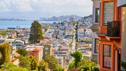 View of San Francisco from top of hill with Victorian houses in foreground.