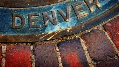 Close-up of Denver title on manhole cover in brick sidewalk or street.