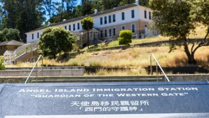Close-up of plaque at Angel Island Immigration Station, California with historic building in background.