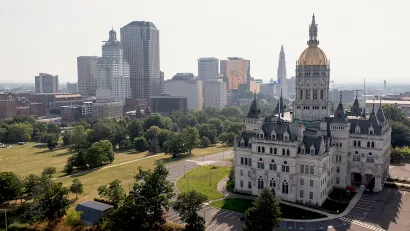 Connecticut state capitol with gold dome and modern office buildings in background in Hartford, CT.