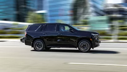 Large black SYV driving down city street with blurred background.