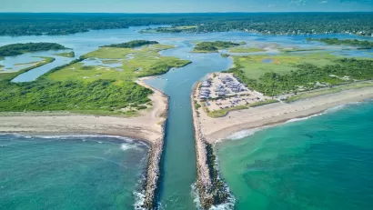 Aerial view of canal cut into beach in Charlestow, Rhode Island with boats parked in sand.