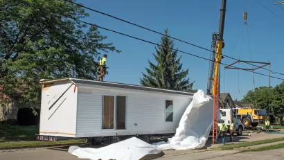 White modular home being installed on a lot.