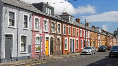 Cars parked along a narrow street with colorful two-story houses in Dublin, Ireland.