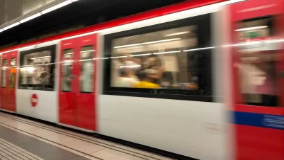 Red and white Barcelona Metro train passing through station.