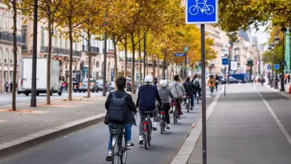 People on bikes ride on protected bike path along the Seine River in Paris, France