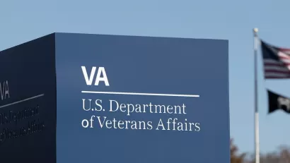Close-up of Department of Veterans Affairs sign in Washington, D.C. with American and MIA flags on flagpole in background.