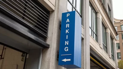 Blue sign with white Parking text and arrow pointing into garage