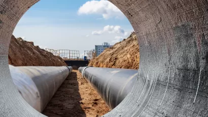 View from inside large wastewater pipe laid ina trench looking out at construction site