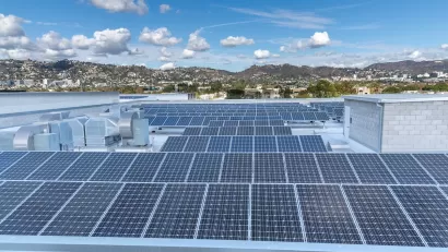 Large roof with solar panels and Los Angeles hills in background.