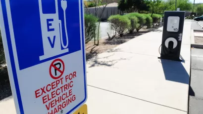 Close-up of EV charging station sign with "No Parking except for EV charging" in outdoor parking lot.