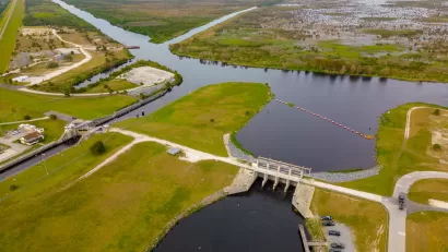 An aerial view of a lock and dam between two waterways with miles of marshes into the background of the image.