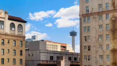View of rotating restaurant tower in downtown San Antonio, Texas through older brick high-rise buildings.