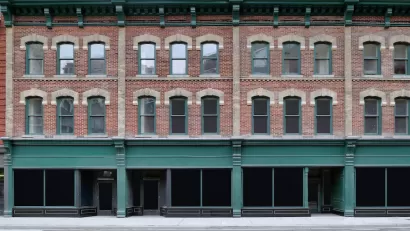 Brick building with storefronts on ground floor and apartments on two floors above.