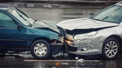 Two cars crashed head-on into each other on wet asphalt road.