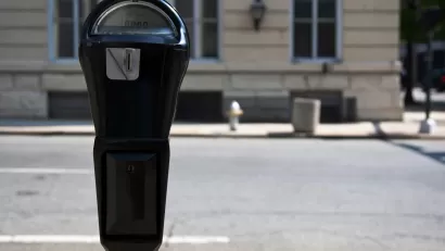 Close-up of black parking meter with blurred street in background