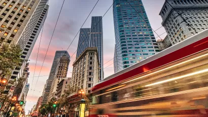Blurred red San Francisco streetcar speeding past tall downtown buildings