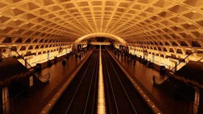 View of expansive subway station with curved roof and passengers waiting for trains in Washington, D.C.