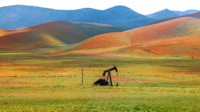 Abandoned oil well against hill covered in blooming orange flowers in Carrizo Plain National Monument, California.