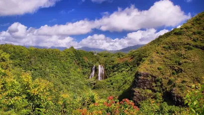 'Opaeka'a Falls on the island of Kauai surrounded by lush green forest and blue sky.