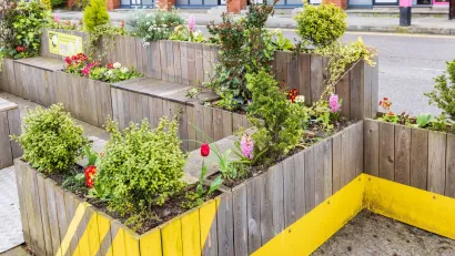 Parklet with wooden benches and flower boxes on street in Ireland.