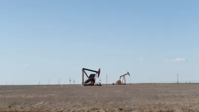 Two oil drilling derricks in vast field in West Texas.