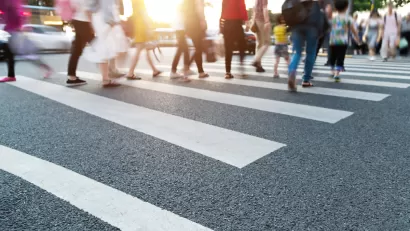 Close-up of blurred pedestrians crossing busy urban crosswalk.