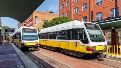 Two yellow and white Dallas Area Rapid Transit light rail streetcars at station in Dallas, Texas.