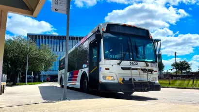 Houston Metro bus at a bus stop with bright blur cloudy sky in background