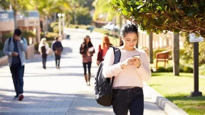 Students walking on sunny walkway on college campus.