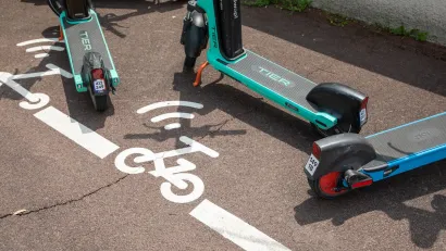 Close-up on e-scooters parked in painted designated parking area on city street.