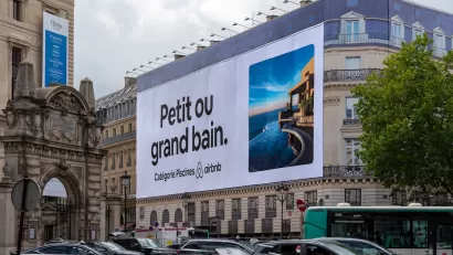 Large Airbnb billboard on neoclassical apartment building in Paris, France.