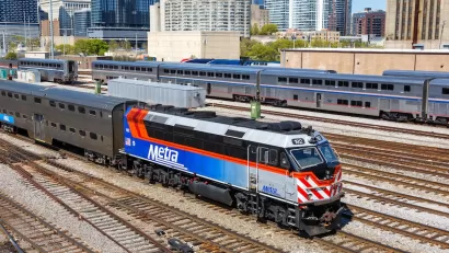 Blue, white, and red Metra commuter train with Chicago buildigns in background.